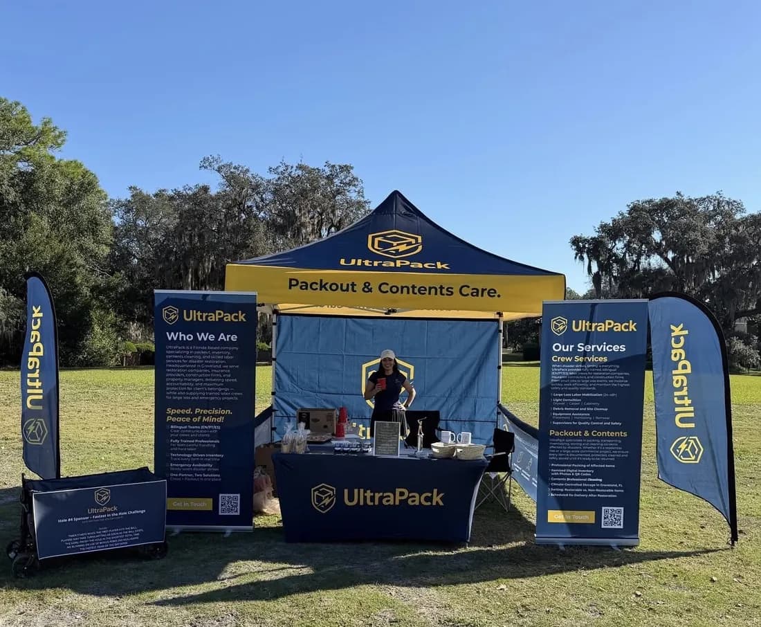 UltraPack canopy tent with roll-up banners, feather flags and a fitted table cover at an outdoor event